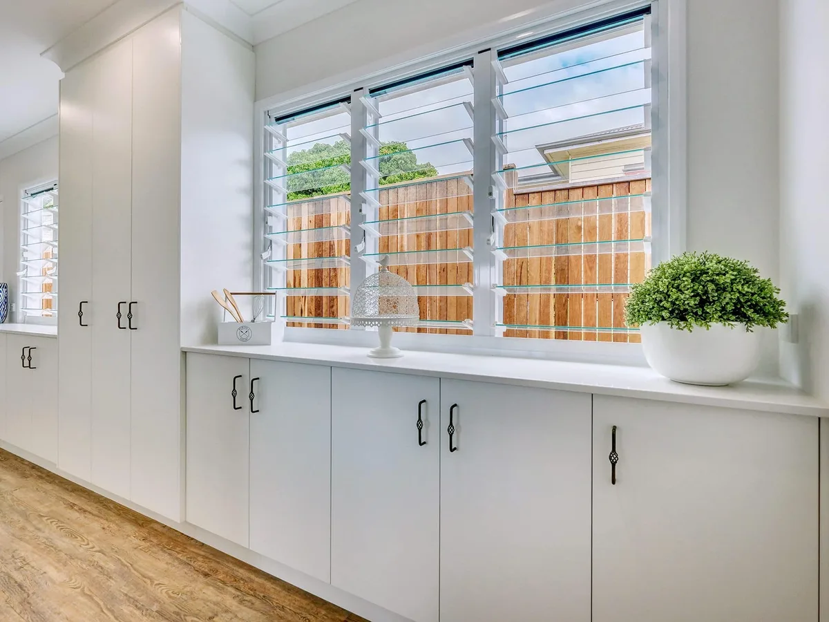 Custom laundry cabinetry with louvre windows by MGH