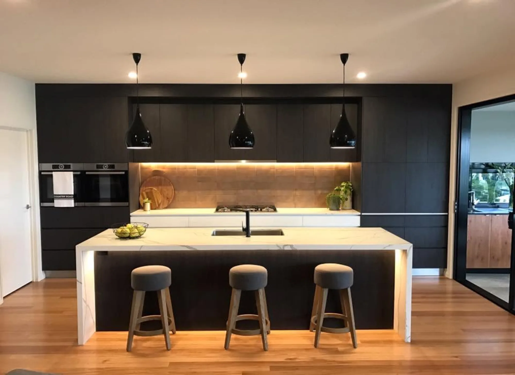 Dark island kitchen with stone benchtop and timber floor built by MGH Cabinetmaking